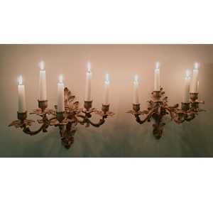 Pair of five light gilt sconces with candles on a wall