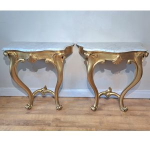 A pair of gilt console tables with shell detail and white marble tops
